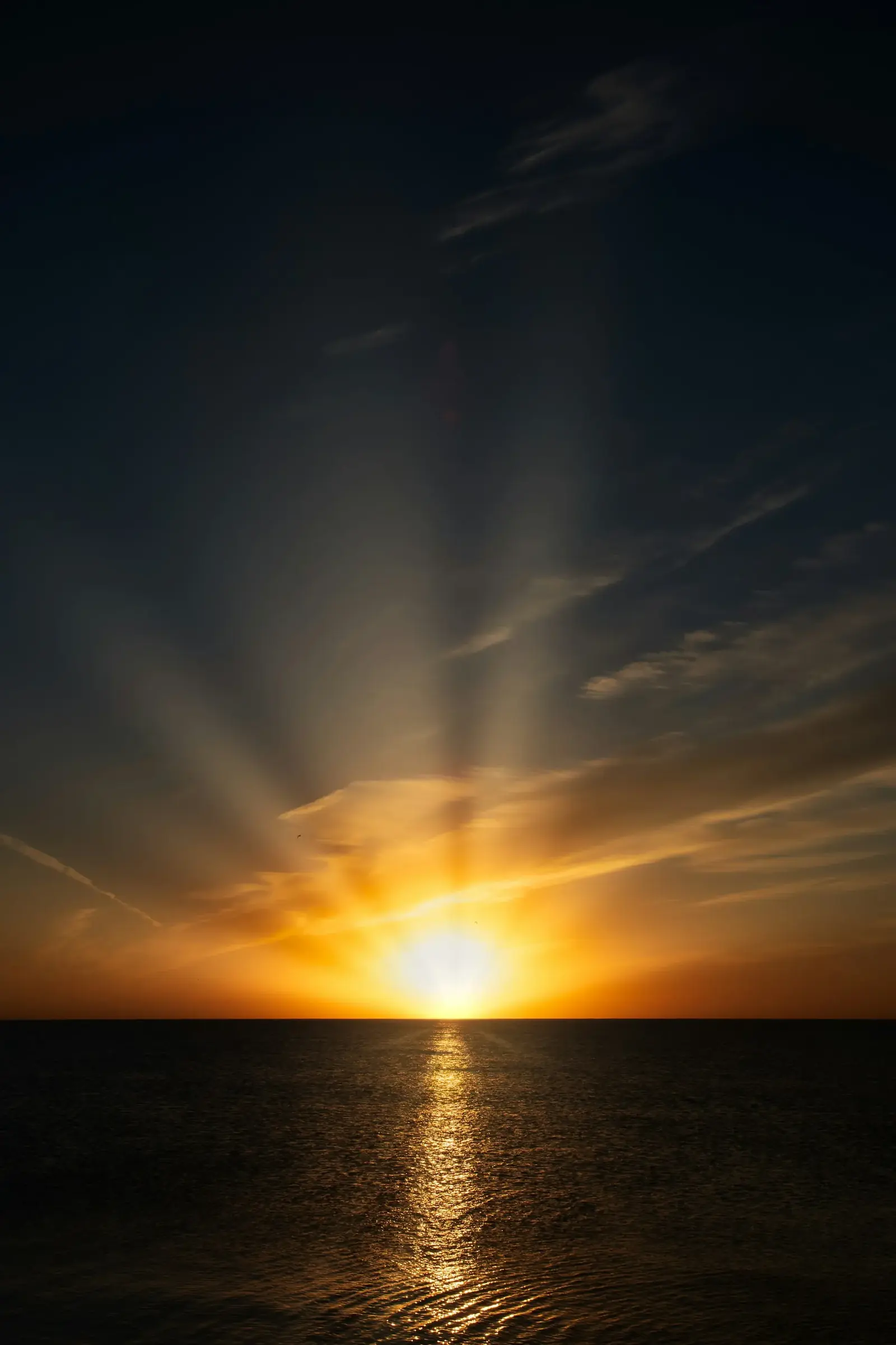 Sonnenaufgang über dem Meer mit Lichtstrahlen und Spiegelung auf dem Wasser