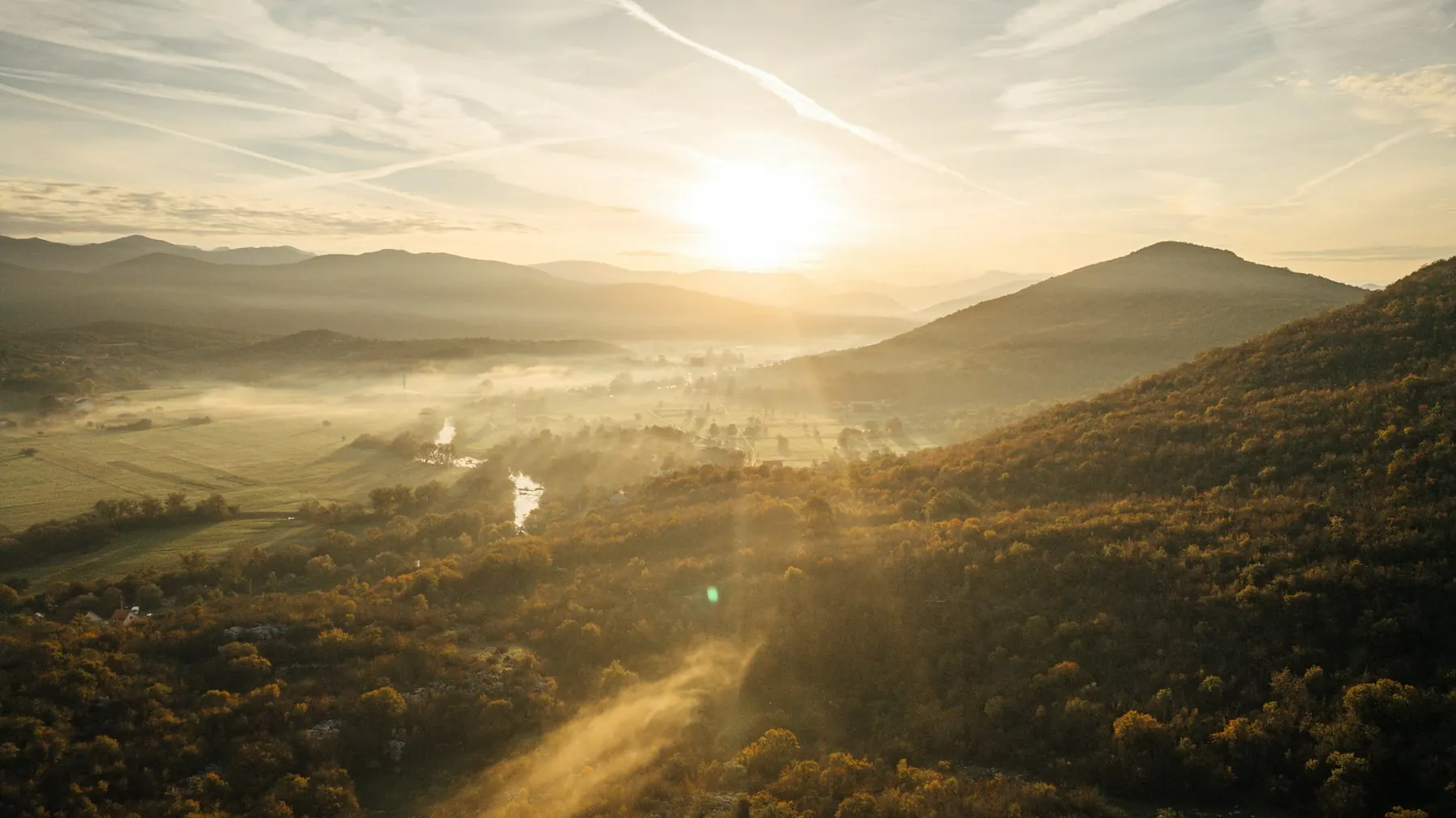 Hügelige Tallandschaft im Morgennebel bei Sonnenaufgang